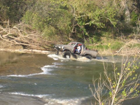 2001 Jeep Wrangler - Pickup truck navigates a river crossing, kicking up water.