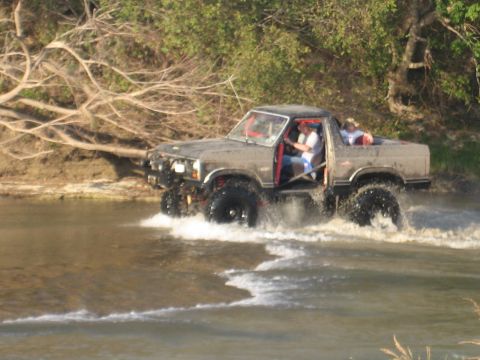 2001 Jeep Wrangler - This modified pickup truck is navigating a water crossing with people inside.