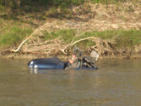 2001 Jeep Wrangler - A person is in a blue vehicle that is partially submerged in a river.
