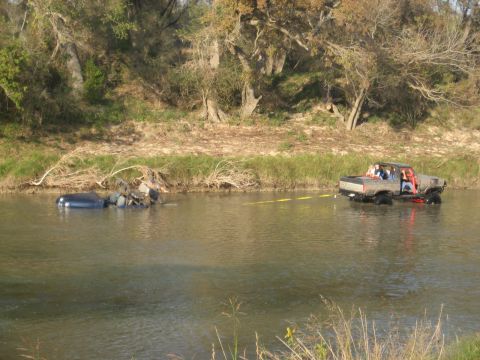 2001 Jeep Wrangler - A pickup truck tows a submerged sedan out of a river.