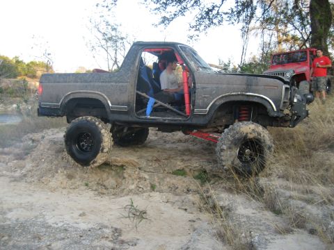2001 Jeep Wrangler - A heavily modified pickup truck navigates rough terrain, with another vehicle visible in the background.