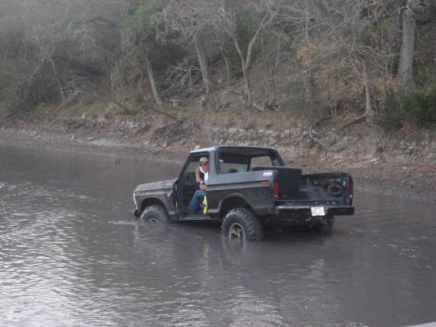 2001 Jeep Wrangler - A black 1978 Ford Bronco is partially submerged in murky water with a person sitting in the driver's seat.
