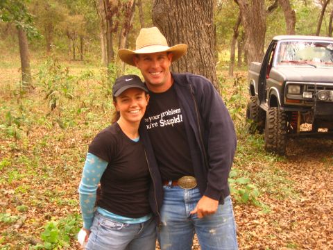 2001 Jeep Wrangler - A couple smiles for the camera with a , lifted truck in the background.