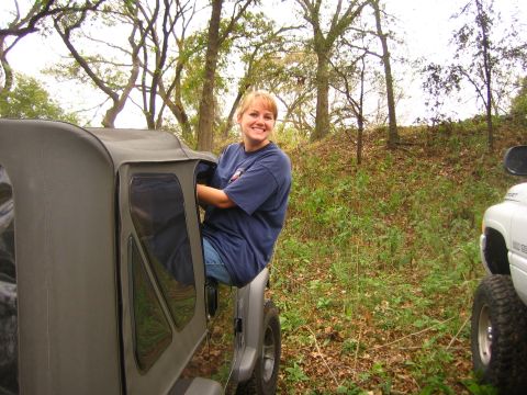 2001 Jeep Wrangler - A woman smiles while sitting in the open door of a gray Jeep Wrangler.