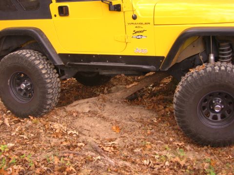 2001 Jeep Wrangler - Side view of a yellow 2001 Jeep Wrangler 4.0L Sport model on an off-road trail.