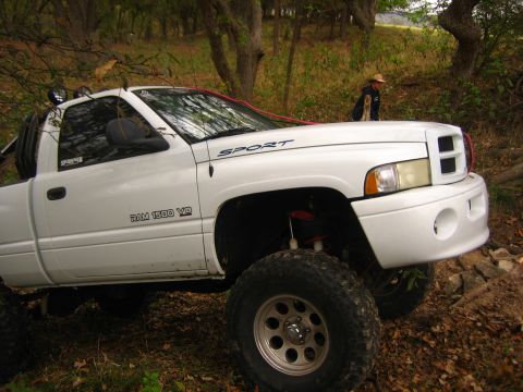 2001 Jeep Wrangler - A lifted white Dodge Ram 1500 pickup truck is shown off-road with large tires and suspension modifications.
