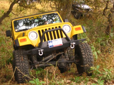 2001 Jeep Wrangler - A yellow 2001 Jeep Wrangler is parked off-road, with another vehicle visible in the background.