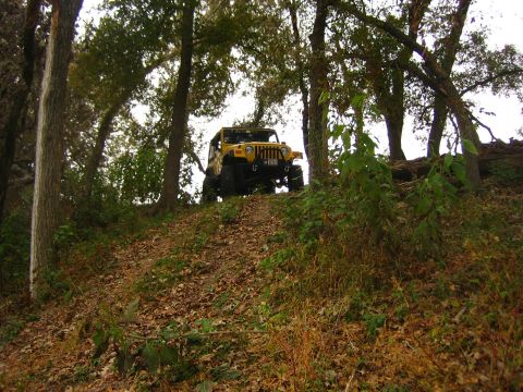 2001 Jeep Wrangler - Yellow 2001 Jeep Wrangler navigates an incline in a wooded area.