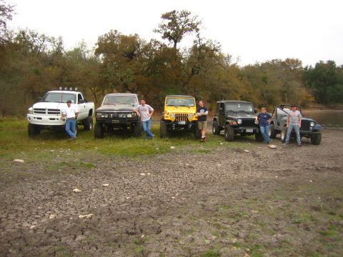 2001 Jeep Wrangler - A group of friends and their off-road vehicles pose for a photo by a body of water.
