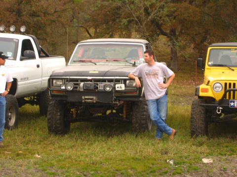 2001 Jeep Wrangler - A yellow 2001 Jeep Wrangler is parked next to a black truck with a man leaning on it.