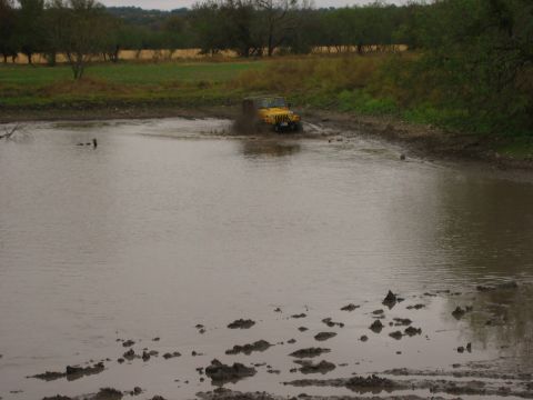 2001 Jeep Wrangler - A yellow 2001 Jeep Wrangler navigates through a muddy off-road obstacle.