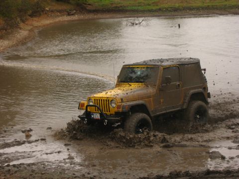2001 Jeep Wrangler - Yellow 2001 Jeep Wrangler navigates a muddy water obstacle, kicking up spray.