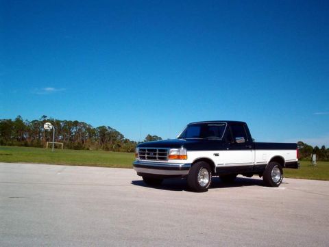 1995 Ford F-150 - This two-tone Ford F-150 pickup truck is shown from the front three-quarter angle under a clear blue sky.