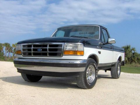 1995 Ford F-150 - This two-tone black and white 1995 Ford F-150 pickup truck is shown from a three-quarter front angle.