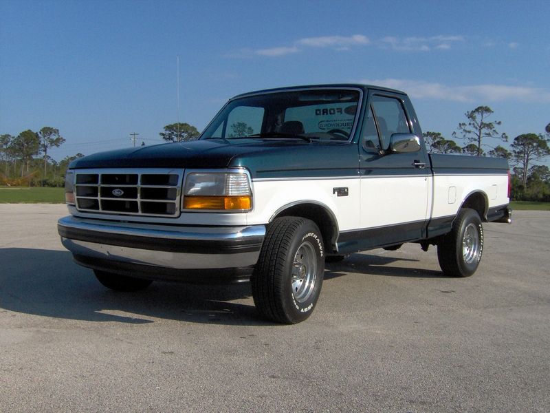 1995 Ford F-150 pickup truck, dark green and white two-tone paint, parked on asphalt