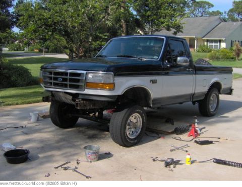 1995 Ford F-150 - A two-tone black and silver Ford F-150 truck is shown with its front end lifted and suspension components visible.