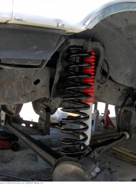 1995 Ford F-150 - A close-up view shows a newly installed coil spring and red shock absorber boot on a truck's suspension system.