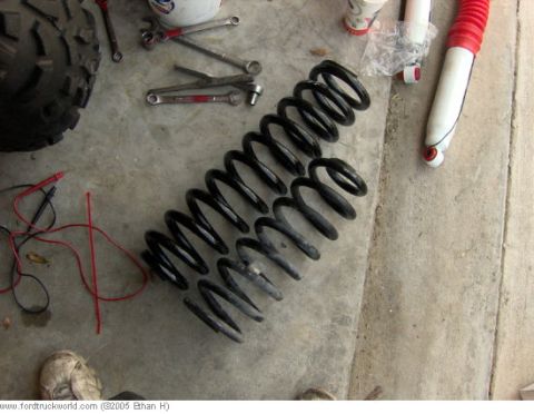 1995 Ford F-150 - Suspension components, including coil springs and a shock absorber, are laid out on a concrete surface with tools and a tire nearby.
