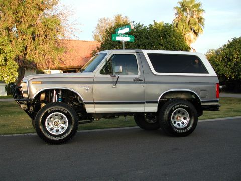 1980 Ford Bronco - This modified Ford Bronco features an elevated suspension and custom front bumper, parked curbside.