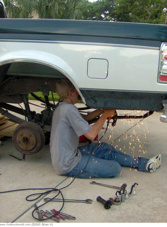 1995 Ford F-150 side view, person grinding on frame near rear axle