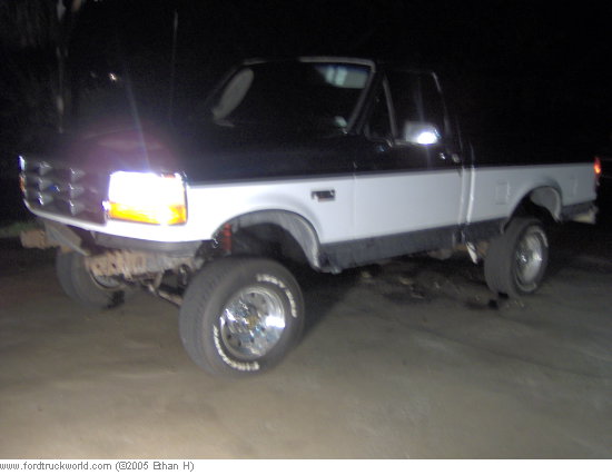 Pickup truck with lifted suspension and aftermarket wheels, parked at night