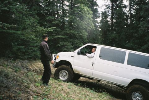 2000 Ford E350 - White Ford E350 van navigates a steep, wooded dirt path.