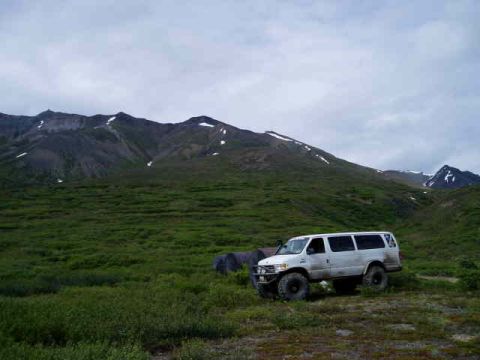 2000 Ford E350 - A white Ford E350 van is parked in a grassy field, with large mountains visible behind it.