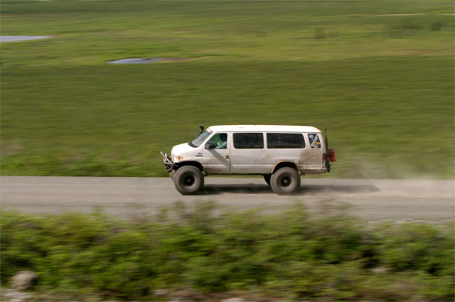 White 2000 Ford E350 van with off-road tires on a dirt road