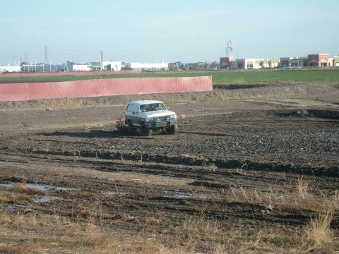 1989 Ford Bronco - Ford Bronco navigating a muddy construction site under a clear sky.