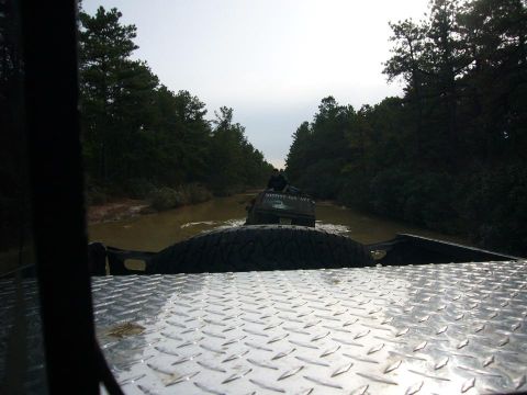 1989 Jeep Cherokee - Two SUVs navigate a muddy path surrounded by trees.