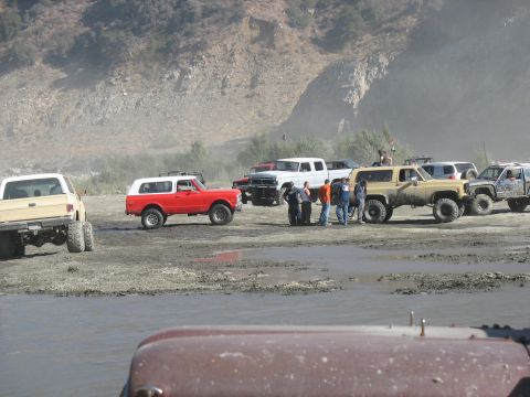 1987 Ford Bronco - A group of off-road vehicles are gathered in a muddy area, possibly for an event or outing.
