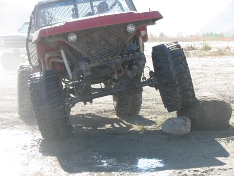 1987 Ford Bronco - A heavily modified off-road vehicle navigates rough terrain, with a second vehicle visible in the background.