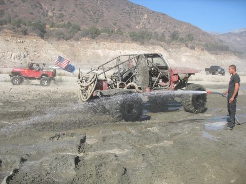 1987 Ford Bronco - A custom buggy is being sprayed with water while another off-road vehicle flies an American flag in the background.