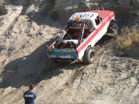 1987 Ford Bronco - This modified truck, likely from the late 1970s, navigates a steep, sandy incline.