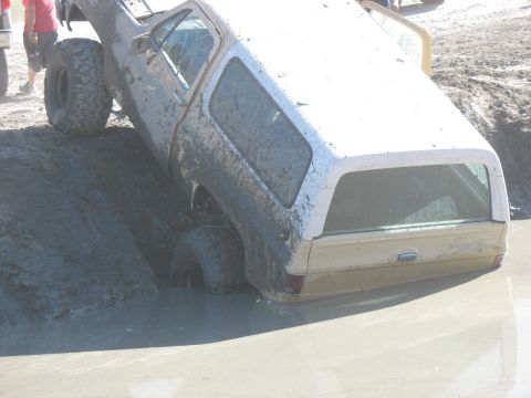 1987 Ford Bronco - This vehicle is deeply stuck in thick mud, with only its upper body and tires visible above the mire.