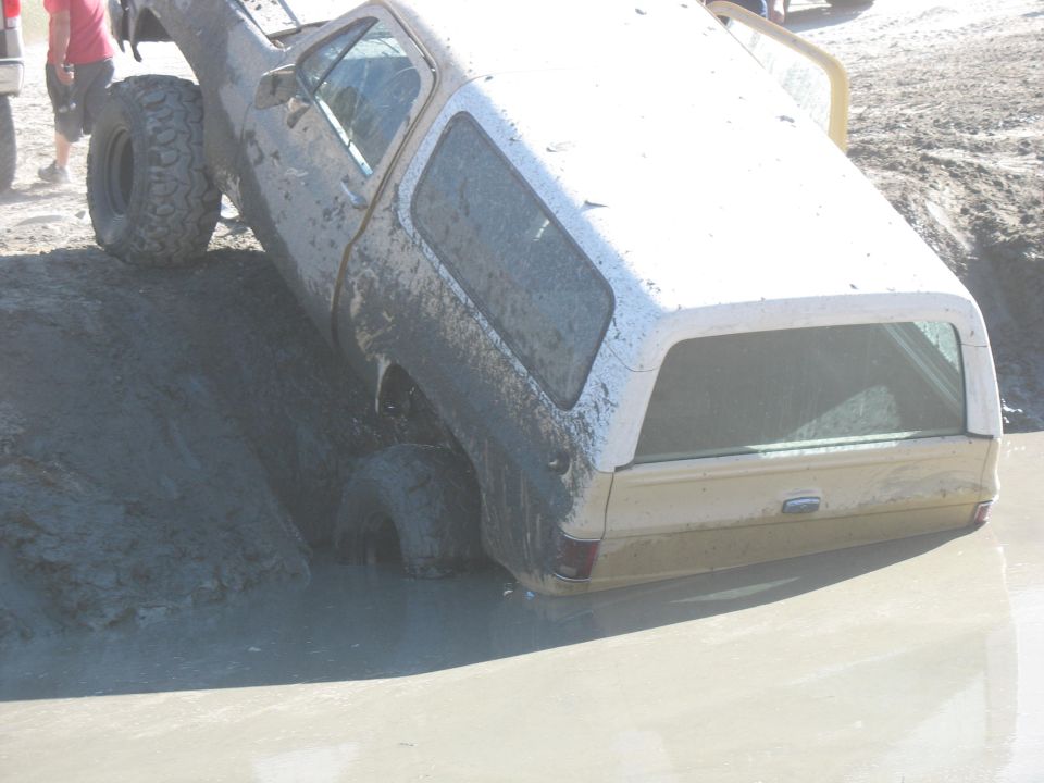 muddy SUV stuck in a mud pit, tires submerged