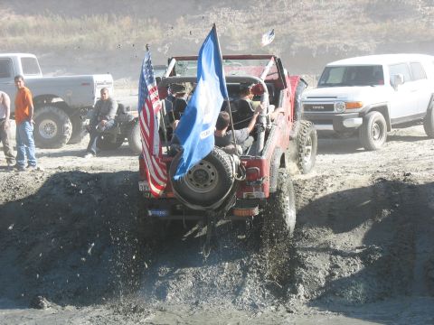 1987 Ford Bronco - Off-roading in a red Jeep Wrangler, with other vehicles nearby.