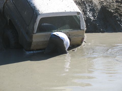 1987 Ford Bronco - Person attempts to free a 1987 Ford Bronco that is stuck in deep mud.