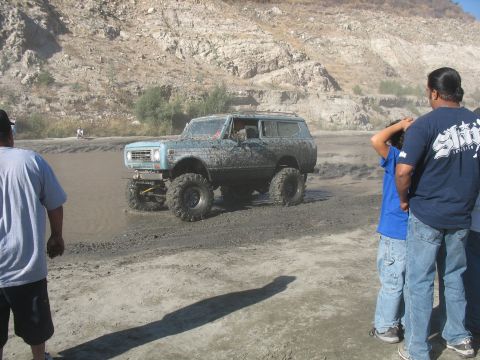 1987 Ford Bronco - SUV navigating a muddy, watery terrain with onlookers present.