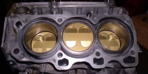 1996 Ford Probe - Close-up view of an engine block showing three pistons within their cylinders.