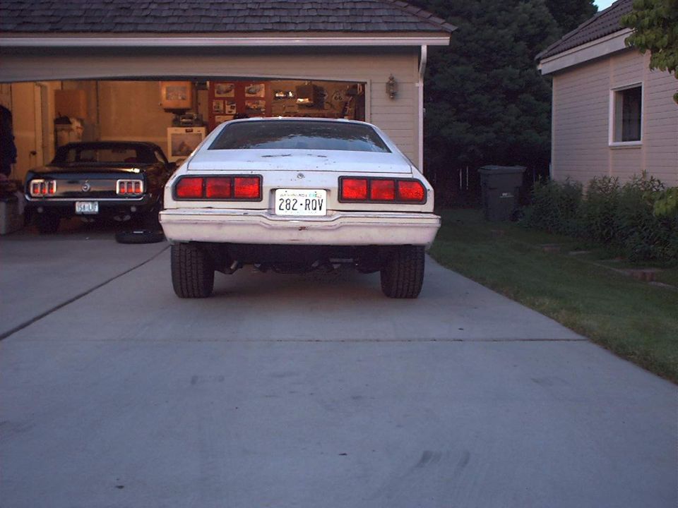rear view of white sedan with license plate 282-ROV, black car in garage behind it