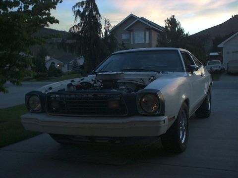 1978 Ford Mustang II - A white 1975 Ford Mustang II is parked in a driveway with its hood open, revealing the engine.