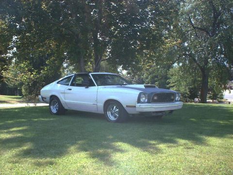 1978 Ford Mustang II - A white Ford Mustang II is parked on a grassy lawn under shady trees.