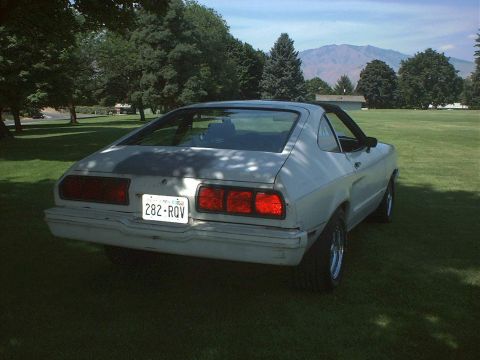 1978 Ford Mustang II - The rear of a 1978 Ford Mustang II is visible on a grassy field under a clear sky.