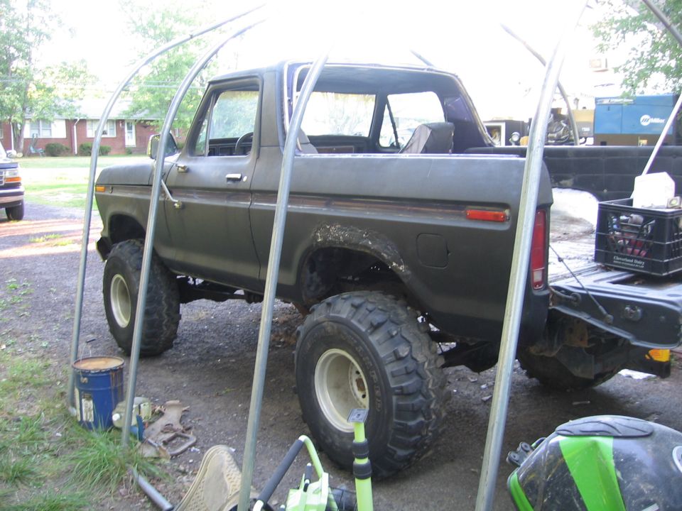 1978 Ford Bronco parked under a carport with large off-road tires