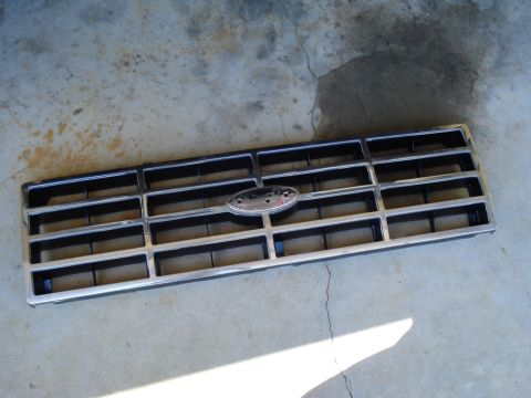 1984 Ford Bronco - This grille, likely from a 1984 Ford Bronco, features a chrome surround and horizontal black bars.