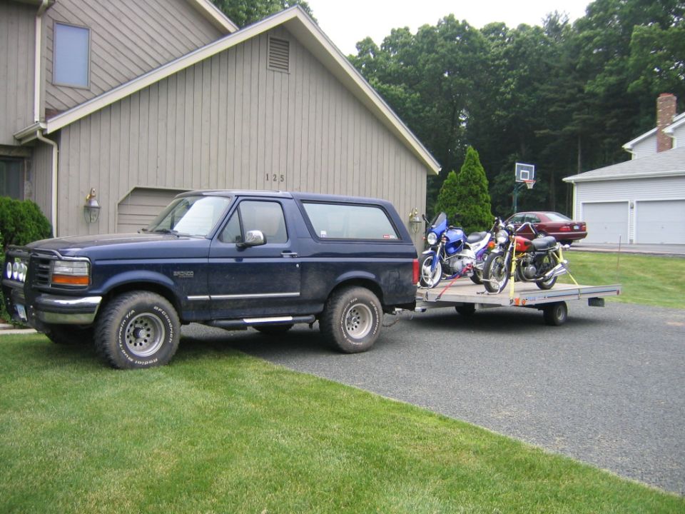Blue Ford Bronco towing a trailer loaded with motorcycles