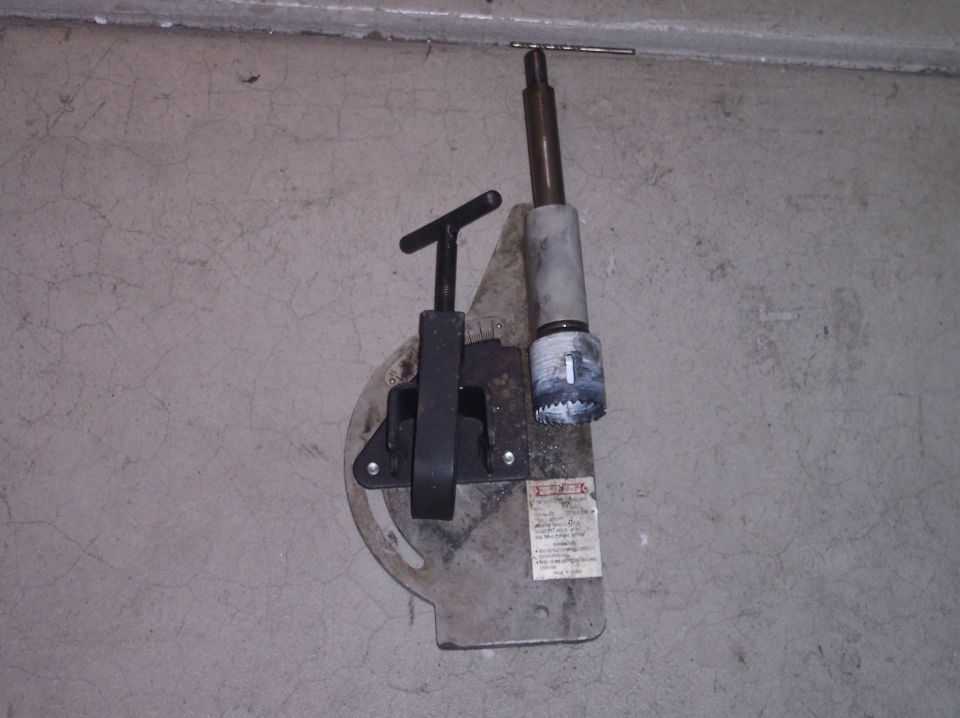 Drill press attachment with a hole saw and drill bit mounted