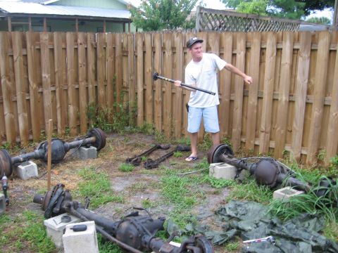 1995 Ford F-150 - Man with pipe wrench in yard surrounded by several truck axles.