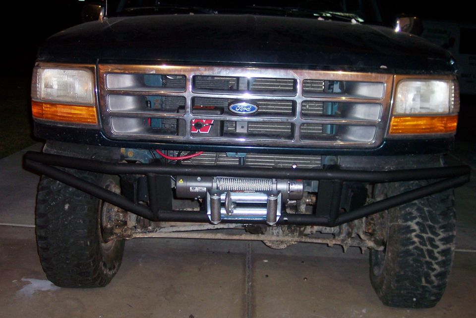 Ford truck front end, grille has Ford logo, aftermarket bumper with winch